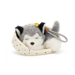 Plush, fluffy sleeping husky puppy resting in a polka dot little bed.